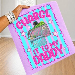 May include: A light purple fabric square featuring a central design with light blue vertical stripes, pink stars, and a scalloped border. The text reads CHARGE IT TO MY DADDY in pink. A wallet and credit cards with daisy accents are illustrated.