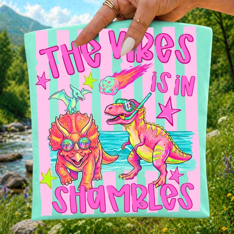 Close-up mockup of the 'Vibes In Shambles' T-Rex and Triceratops design on apparel.