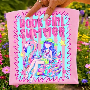 May include: A light pink tote bag featuring a graphic print with the text BOOK GIRL SUMMER in bold pink letters. The illustration shows a person wearing a hat and reading a book while sitting on a large, iridescent pink flamingo pool float.