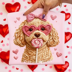 May include: A pink pillow featuring an embroidered poodle wearing heart-shaped sunglasses and a bow. The poodle is holding a lollipop. Pink embroidered hearts and red heart-shaped balloons decorate the background.