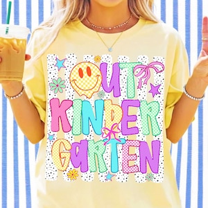 Puede incluir: Una camiseta de color amarillo p&aacute;lido con un estampado gr&aacute;fico que incluye el texto "OUT KINDERGARTEN" en letras de burbuja coloridas y estampadas. El dise&ntilde;o incluye una cara sonriente a cuadros amarillos, lazos rosas, estrellas peque&ntilde;as y flores sobre un fondo de rayas negras punteadas.