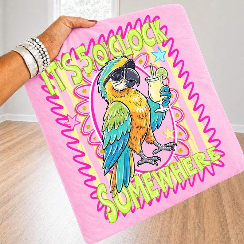 May include: Pink blanket featuring a cartoon parrot wearing sunglasses and holding a cocktail. The blanket has the text "IT'S 5 O'CLOCK SOMEWHERE" in green and yellow. The parrot is yellow, blue, and green.