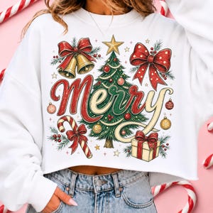 May include: A white long-sleeve sweatshirt featuring a graphic print of a green Christmas tree, red bows, gold bells, a candy cane, and a gift box. The word Merry is written in large red and gold script across the center of the design.