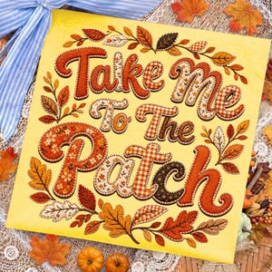 May include: A square yellow sign featuring the text Take me To The Patch in decorative, multi-patterned orange and brown lettering. The text is surrounded by an intricate border of illustrated autumn leaves in shades of red, orange, and gold.