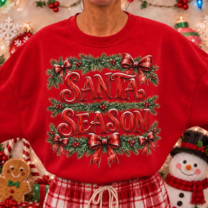 以下が含まれることがあります： 赤い文字でSANTA SEASONと書かれた鮮やかな赤色のクルーネックのスウェットシャツ。デザインは緑の松の枝、赤いベリー、そして長方形のグラフィックの四隅に配置された4つの赤のチェック柄のリボンで縁取られています。