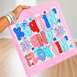 Op de afbeelding: Een vierkante roze kussensloop met de tekst "BOATIN' AND FLOATIN'" in grote, veelkleurige letters met patronen. Het ontwerp bevat rood, blauw en lichtblauw geblokte en gestippelde patronen, kleine sterretjes, bloemen en vuurwerk.
