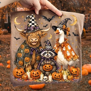May include: A tan fabric print featuring a Highland cow, a raccoon, and a goose wearing witch hats and Halloween costumes. The animals are surrounded by pumpkins, bats, and crescent moons. The goose wears a cape with a ghost pattern.