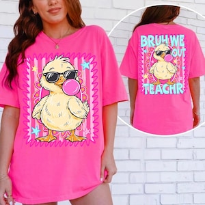 K&ouml;nnte beinhalten: Ein leuchtend pinkfarbenes T-Shirt mit einem Cartoon-K&uuml;ken, das eine Sonnenbrille tr&auml;gt und eine Blase bl&auml;st. Das Frontdesign ist mit einem rosa-wei&szlig; gestreiften Rahmen mit Sternen versehen. Auf der R&uuml;ckseite des Shirts steht "BRUH WE OUT TEACHR".