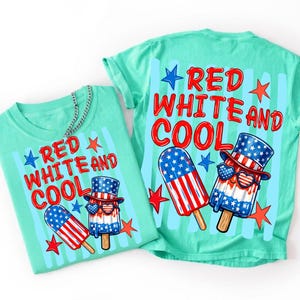 May include: A mint green t-shirt featuring a graphic of two popsicles with red, white, and blue star and stripe patterns. One popsicle wears a top hat and heart-shaped sunglasses. The text reads RED WHITE AND COOL in red letters.