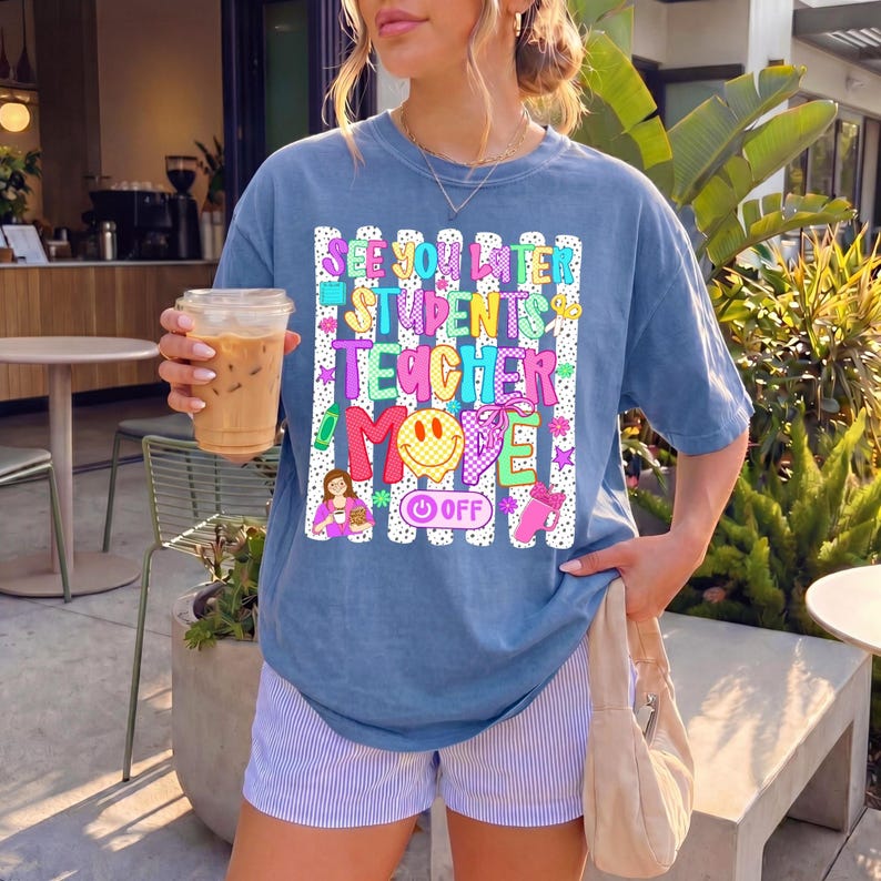 K&ouml;nnte beinhalten: Ein blaues Kurzarm-T-Shirt mit einem Grafikdruck aus wei&szlig;en vertikalen Streifen und buntem Text mit der Aufschrift "SEE YOU LATER STUDENTS TEACHER MODE OFF". Das Design enth&auml;lt ein gelbes Smiley-Gesicht, einen Stift und eine Lehrer-Illustration.