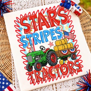 以下が含まれることがあります： 赤い「STARS」、青い「STRIPES」、赤い「TRACTORS」の文字がプリントされた白いTシャツ。デザインには、干し草の俵を積んだ木製の荷車を引く緑色のトラクター、小さなアメリカ国旗、黄色いスマイリーフェイスが描かれています。