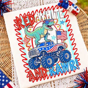 Może przedstawiać: Biała koszulka z grafiką zielonego dinozaura w okularach przeciwsłonecznych z motywem flagi amerykańskiej, stojącego na monster trucku z wzorami flagi. Napis głosi RED WHITE AND RAWR! z czerwonymi i niebieskimi falistymi obw&oacute;dkami.