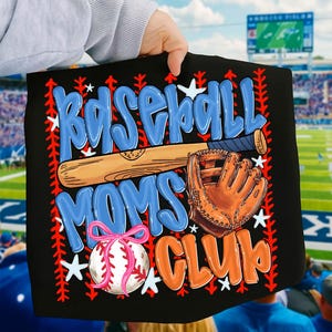 May include: Black baseball-themed graphic with the words "Baseball Moms Club" in blue and orange. A baseball bat, glove, and baseball with a pink bow are also featured. White stars and red stitching accents complete the design.