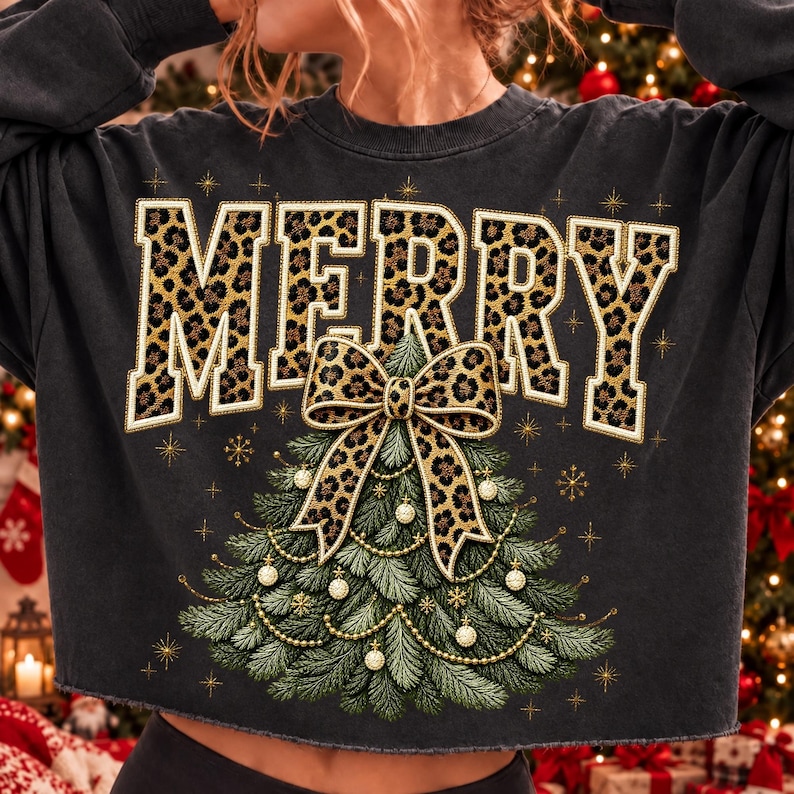 Op de afbeelding: Een antracietgrijs sweatshirt met lange mouwen en het woord MERRY in grote blokletters met een luipaardprint. Onder de tekst staat een afbeelding van een groene kerstboom versierd met gouden kralen en een grote strik met luipaardprint.
