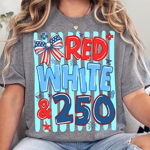 Peut inclure: Un t-shirt gris chin&eacute; avec une impression graphique &agrave; rayures verticales bleu clair. Le texte indique RED WHITE & 250 en rouge, bleu clair et bleu fonc&eacute;. Un n&oelig;ud patriotique, des &eacute;toiles et des feux d'artifice ornent le motif.