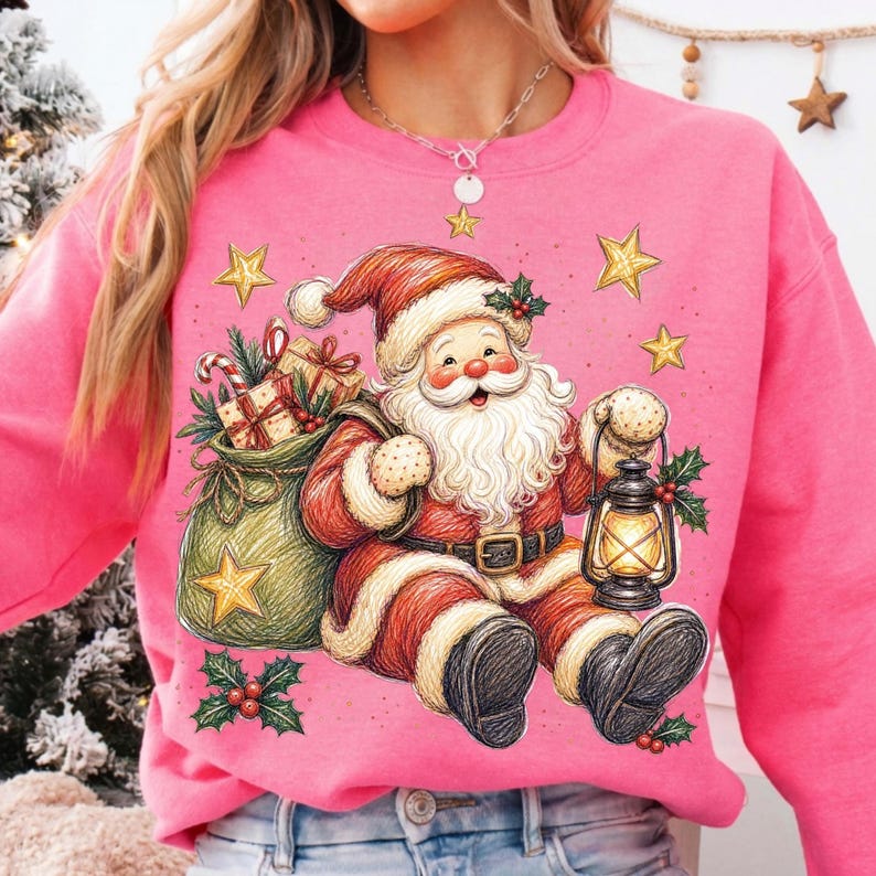 K&ouml;nnte beinhalten: Ein leuchtend pinkfarbenes Sweatshirt mit Rundhalsausschnitt und einer grafischen Illustration des Weihnachtsmanns in einem roten Anzug mit wei&szlig;em Pelzbesatz, der eine leuchtende Laterne und einen gr&uuml;nen Geschenkesack h&auml;lt.