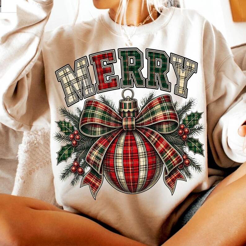 Puede incluir: Una sudadera color crema con la palabra MERRY en una fuente de cuadros. Debajo del texto hay un gr&aacute;fico de un adorno navide&ntilde;o redondo con un gran lazo de cuadros, rodeado de hojas de acebo verdes y peque&ntilde;as bayas rojas en un dise&ntilde;o festivo.