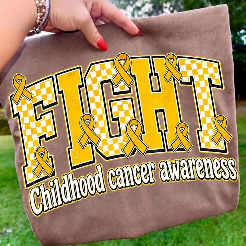 May include: A brown tote bag featuring a large graphic with the word FIGHT in bold yellow and white checkered block letters. Multiple yellow awareness ribbons are placed around the text, with the words childhood cancer awareness below.
