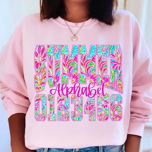 K&ouml;nnte beinhalten: Ein hellrosa Sweatshirt mit dem Wort "SUMMER" in gro&szlig;en, farbenfrohen Blumenbuchstaben. Darunter steht das Wort "Alphabet" in Schreibschrift, gefolgt von den Zahlen 0-6, ebenfalls in einem floralen Design. Das Sweatshirt ist ein l&auml;ssiger Stil.