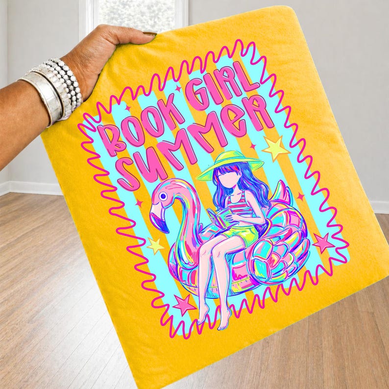 May include: A yellow square pillowcase featuring a graphic print of a person in a sun hat reading a book while sitting on a pink flamingo pool float. The text BOOK GIRL SUMMER is printed in pink above the illustration, surrounded by a wavy border.