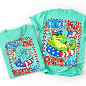 May include: A mint green t-shirt featuring a graphic of the Statue of Liberty and an alligator in a patriotic inner tube. The text reads CHILL THE FOURTH OUT. The design includes red, white, and blue stars, stripes, and a small American flag.