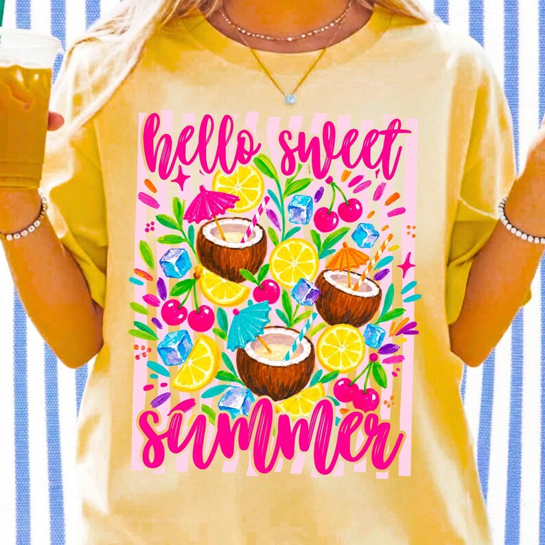 May include: A pale yellow t-shirt featuring a graphic print with the text "hello sweet summer" in pink script. The design includes illustrations of three coconuts with colorful cocktail umbrellas, lemon slices, cherries, and blue ice cubes.
