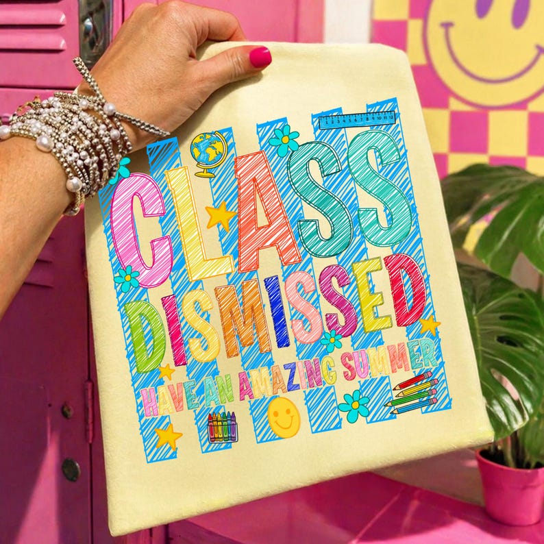 May include: A cream-colored tote bag featuring a colorful graphic with the text "CLASS DISMISSED" and "HAVE AN AMAZING SUMMER." The design includes blue diagonal stripes, a globe, flowers, stars, a smiley face, crayons, and pencils.