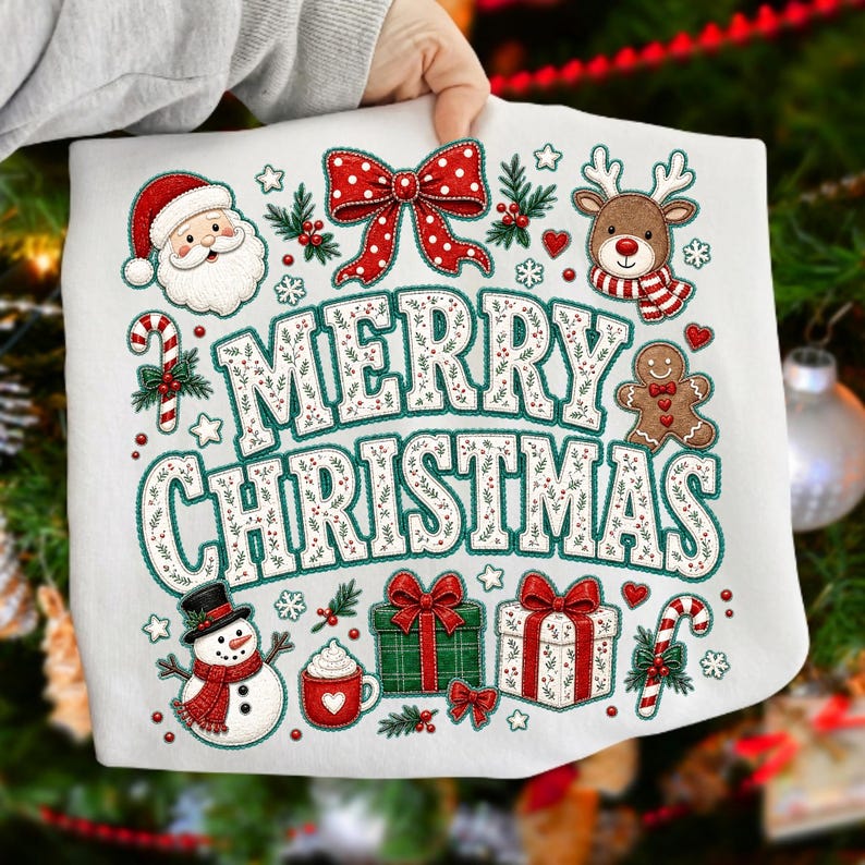 May include: A white sweatshirt featuring a colorful graphic with the text Merry Christmas in large letters. The design includes a Santa Claus, a reindeer, a gingerbread man, a snowman, gift boxes, candy canes, and a red bow with white dots.