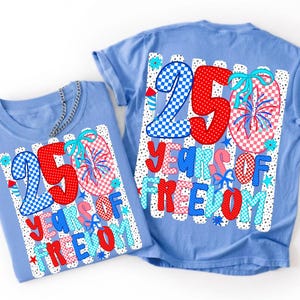 May include: Two light blue t-shirts featuring a graphic design with the text 250 YEARS OF FREEDOM. The design includes red polka dots, blue and white checkerboard patterns, fireworks, and light blue bows on a background of white vertical stripes.