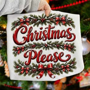 May include: A white fabric item featuring a graphic of green pine branches, red berries, and red bows arranged in a frame. The text "Christmas Please" is printed in a large, bold, red script font across the center of the decorative wreath design.