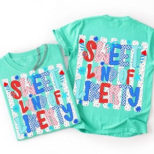 K&ouml;nnte beinhalten: Zwei mintgr&uuml;ne T-Shirts mit einem Grafikdruck, der den Text "SWEET LAND OF LIBERTY" in rot-wei&szlig;-blauen Mustern zeigt. Das Design umfasst vertikale Streifen, Punkte, kleine Blumen und Illustrationen von Feuerwerksk&ouml;rpern auf dem Stoff.