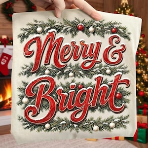 Może przedstawiać: Kremowy kwadrat z tkaniny z czerwonym napisem Merry & Bright wykonanym kursywą. Tekst otoczony jest zielonymi gałązkami sosny, ośnieżonymi igłami oraz małymi czerwonymi i białymi bombkami świątecznymi ułożonymi w ozdobną ramkę.