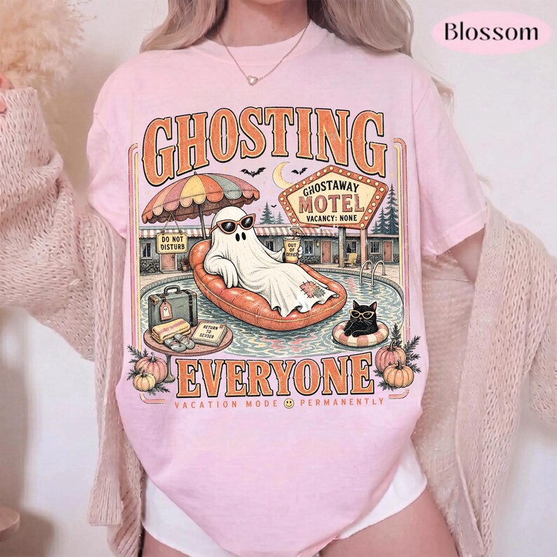 Puede incluir: Una camiseta rosa claro con un gr&aacute;fico de un fantasma con gafas de sol, descansando en un flotador naranja. El texto dice GHOSTING EVERYONE, GHOSTAWAY MOTEL, VACATION MODE PERMANENTLY, DO NOT DISTURB y RETURN TO SENDER. Incluye una ilustraci&oacute;n de un gato negro.