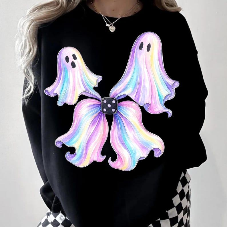 May include: A black long-sleeve sweatshirt featuring a central graphic of four iridescent, pastel-coloured ghosts arranged in a bow shape. The ghosts have soft pink, blue, and yellow gradients, and they are connected by a small black die with white dots.