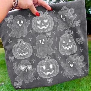 Puede incluir: Un bolso de tela gris oscuro con un patr&oacute;n de l&iacute;neas blancas que muestra varios fantasmas y calabazas. Los fantasmas tienen diferentes expresiones, algunos llevan lazos o gafas en forma de coraz&oacute;n, intercalados con peque&ntilde;as estrellas y lazos.