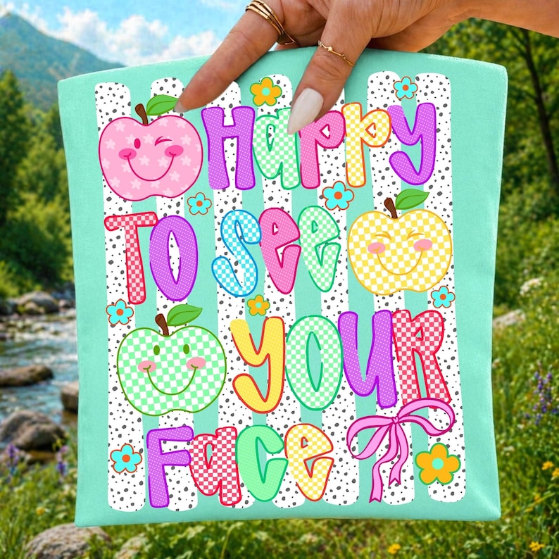 Happy to See Your Face Smiley Apple PNG design on a teacher t-shirt mockup, perfect for back to school sublimation projects.