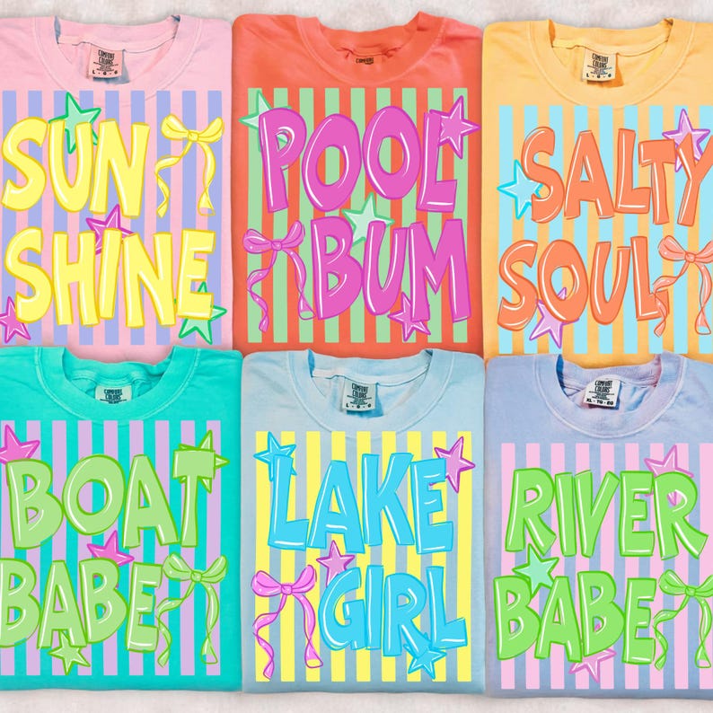 May include: Six colorful t-shirts with summer-themed text designs. The shirts are pink, orange, yellow, teal, light blue, and lavender. Each shirt features a different phrase in bold, colorful letters, such as "Sun Shine" and "Pool Bum".