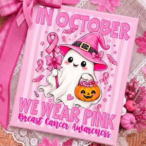 Könnte beinhalten: Ein rechteckiger Leinwanddruck mit einem weißen Geist, der einen rosa Hexenhut trägt, einen rosa Schleifenstab und einen orangefarbenen Kürbiseimer hält. Der Text lautet IN OCTOBER WE WEAR PINK Breast Cancer Awareness auf rosa Streifen.