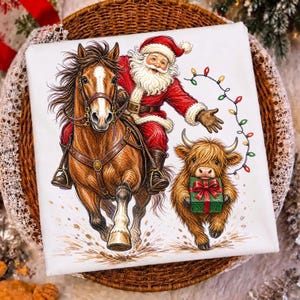Puede incluir: Una camiseta blanca con una ilustraci&oacute;n colorida de Santa Claus montando un caballo marr&oacute;n con una mancha blanca en la cara. Junto a ellos, una peque&ntilde;a y esponjosa vaca Highland lleva un regalo verde con un lazo rojo, rodeada de luces.