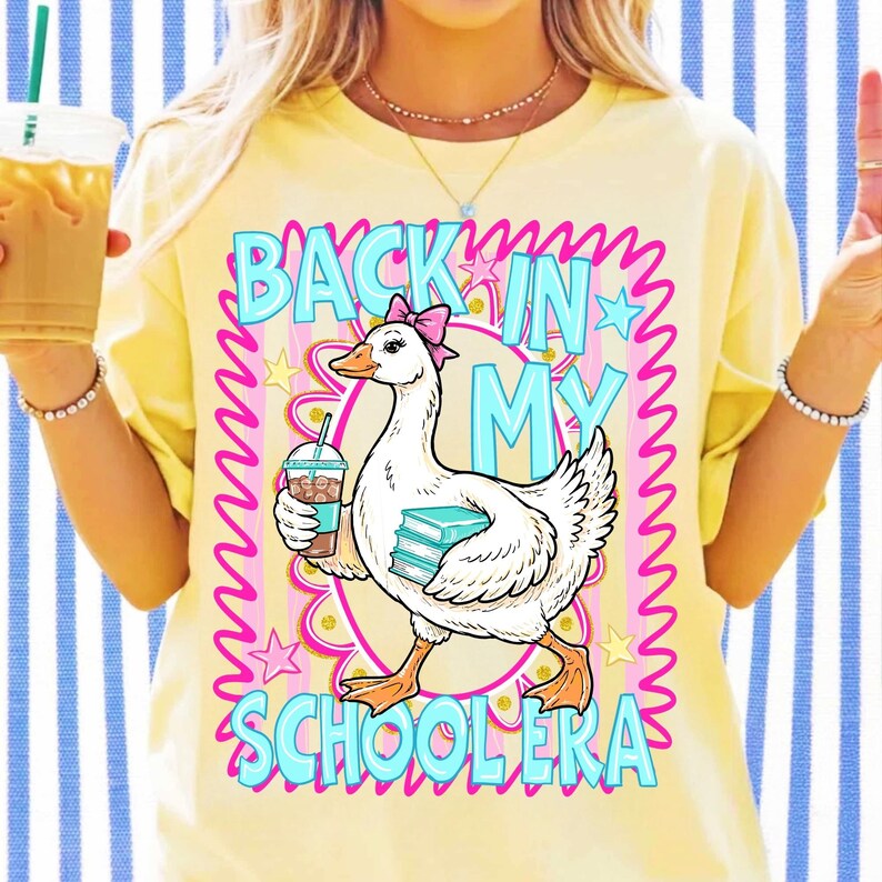 May include: Yellow t-shirt with a graphic of a goose holding a coffee and books, with the text "BACK IN MY SCHOOLERA" in blue and pink. The goose has a pink bow. The shirt is on a person.