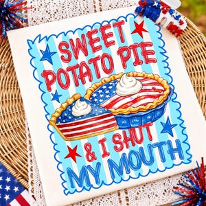 Op de afbeelding: Een wit t-shirt met een afbeelding met de tekst SWEET POTATO PIE & I SHUT MY MOUTH in rood en blauw. Het ontwerp bevat twee taarten versierd met Amerikaanse vlagpatronen, rode sterren en een lichtblauwe gestreepte achtergrond met een schulprand.