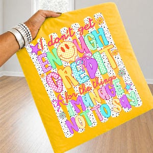 Pode incluir: Um quadrado de tecido amarelo com fundo de bolinhas pretas e brancas e o texto I don't get ENOUGH CREDIT for the things I MANAGE NOT TO SAY, decorado com um smiley amarelo, la&ccedil;os cor-de-rosa e &iacute;cones florais coloridos.