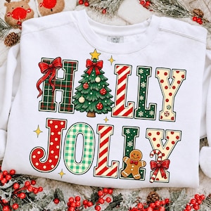 Peut inclure: Un sweat-shirt blanc &agrave; col rond avec l'inscription HOLLY JOLLY dans des motifs de No&euml;l color&eacute;s. Le H est en tartan vert avec un n&oelig;ud rouge, le O est un sapin, les L sont ray&eacute;s et le Y est &agrave; pois. Un bonhomme en pain d'&eacute;pice et une canne sont pr&eacute;sents.