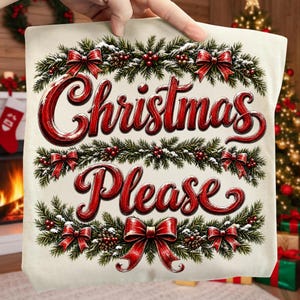 May include: A cream-colored fabric square featuring the red text Christmas Please in a cursive font. The text is framed by green pine branches, red berries, pinecones, and red bows arranged in a decorative border pattern on the front.