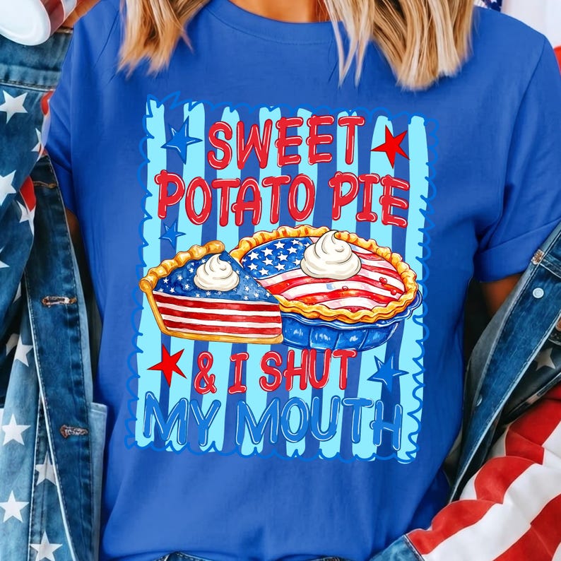 Op de afbeelding: Een koningsblauw t-shirt met een afbeelding van twee taarten met Amerikaanse vlagpatronen en slagroom. De tekst SWEET POTATO PIE & I SHUT MY MOUTH staat in rode en blauwe letters, omringd door rode en blauwe sterren op een gestreepte achtergrond.
