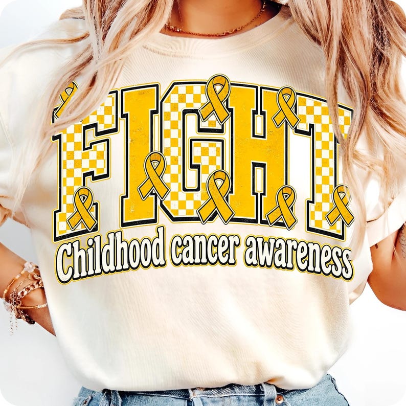 May include: A cream-colored t-shirt featuring the word FIGHT in large, yellow and white checkered block letters with black outlines. Several yellow awareness ribbons are placed around the letters. The text Childhood cancer awareness is below.