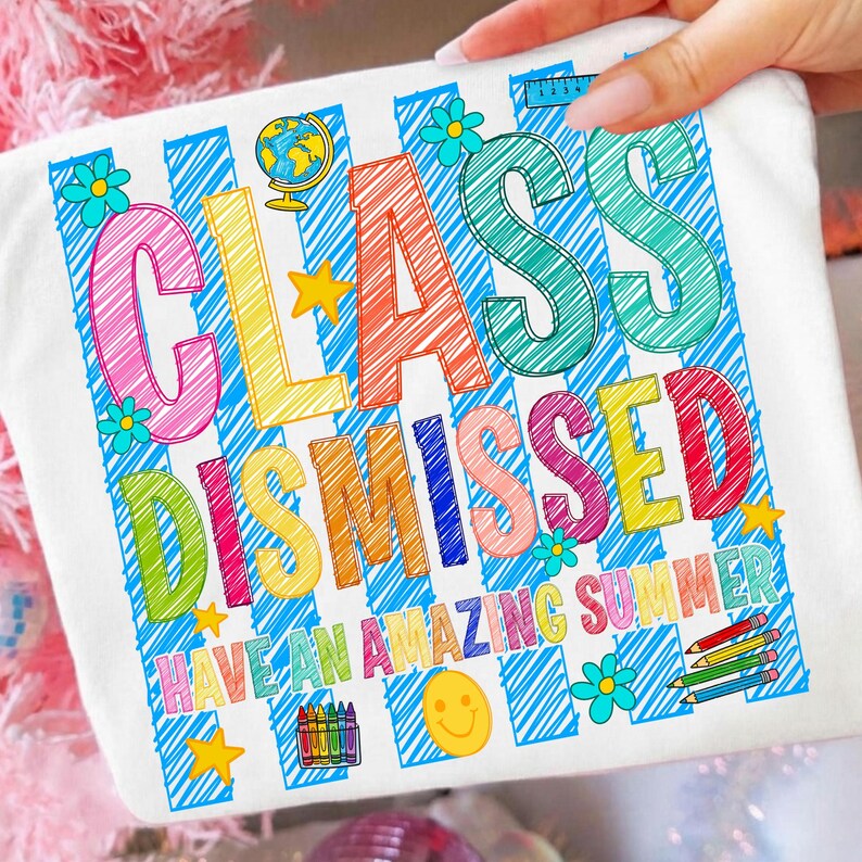 May include: A white t-shirt featuring a colorful graphic with the text "CLASS DISMISSED" and "HAVE AN AMAZING SUMMER." The design includes blue diagonal stripes, a globe, stars, flowers, a smiley face, a ruler, and a set of colored crayons.