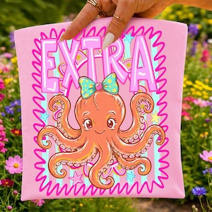 May include: A light pink fabric item featuring a graphic print of an orange octopus with large eyes and a teal polka-dot bow on its head. The word EXTRA is printed in large, bold, light pink letters above the octopus, surrounded by a wavy border.