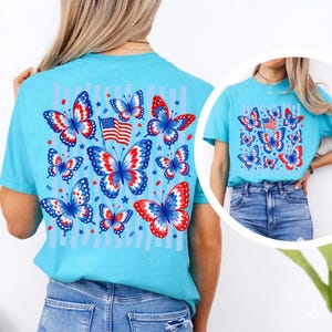 Puede incluir: Una camiseta de manga corta de color turquesa brillante con un gr&aacute;fico grande en la espalda y una versi&oacute;n m&aacute;s peque&ntilde;a en la parte delantera. El dise&ntilde;o muestra varias mariposas en rojo, blanco y azul, junto a una peque&ntilde;a bandera estadounidense y estrellas.