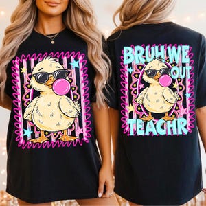 K&ouml;nnte beinhalten: Schwarzes T-Shirt mit einer Cartoon-Ente, die eine Sonnenbrille tr&auml;gt und eine Blase bl&auml;st. Das Frontdesign ist in rosa und wei&szlig;en Streifen mit Sternen eingefasst. Auf der R&uuml;ckseite des T-Shirts steht "BRUH WE OUT TEACHR" in Blau und Rosa.